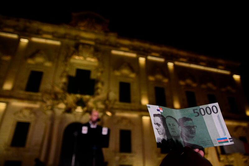A protester holds up a fake banknote showing the faces of Malta's Prime Minister Joseph Muscat and his former chief of staff Keith Schembri. AP