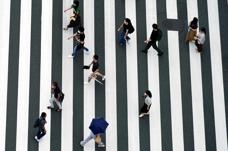 People wearing protective face masks to help curb the spread of the coronavirus walk on a pedestrian crossing in Tokyo Monday,  AP