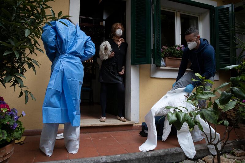 Silvia Mosca, center, welcomes doctor Elisa Riccitelli and nurse Nurse Luigi Lauri as they get ready before administrating a dose of the Pfizer vaccine to her husband at their home in Rome, Tuesday. AP Photo