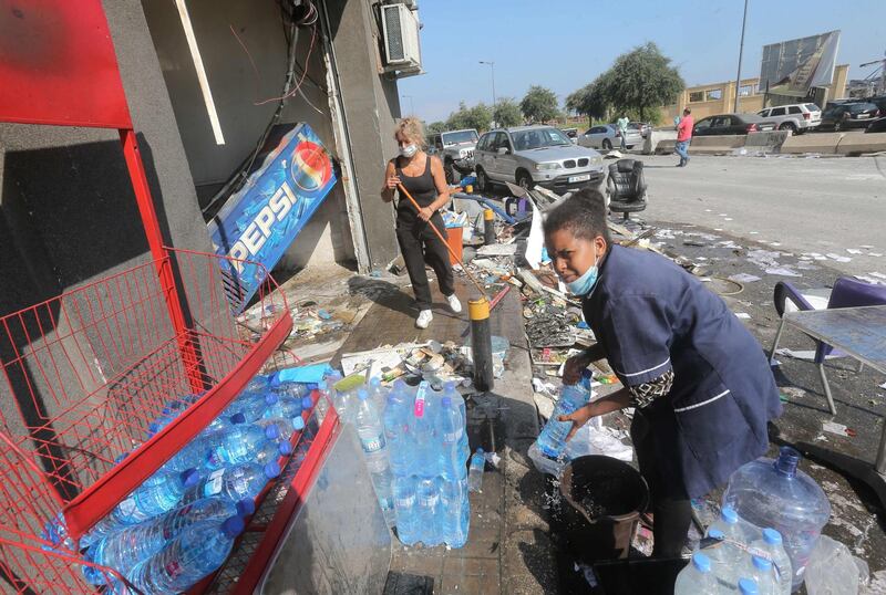 Women clear the damage outside a sideroad kiosk in Beirut.  AFP
