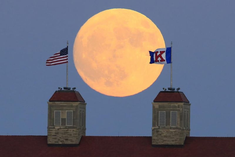 The moon rises beyond flags atop Fraser Hall on the University of Kansas campus in Lawrence, Kansas. Orlin Wagner / AP Photo