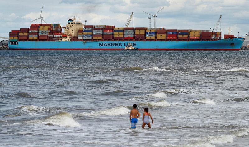 FILE PHOTO: Children play in the sea at New Brighton as the Maersk Line container ship Maersk Sentosa is helped by tugs as it navigates the River Mersey in Liverpool, Britain, July 31, 2018. REUTERS/Phil Noble/File Photo               GLOBAL BUSINESS WEEK AHEAD