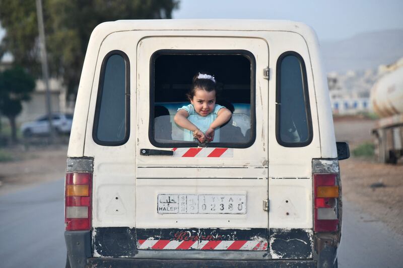 A Syrian girl looks out of the rear window of a vehicle transporting families celebrating Eid Al Fitr in Afrin. AFP