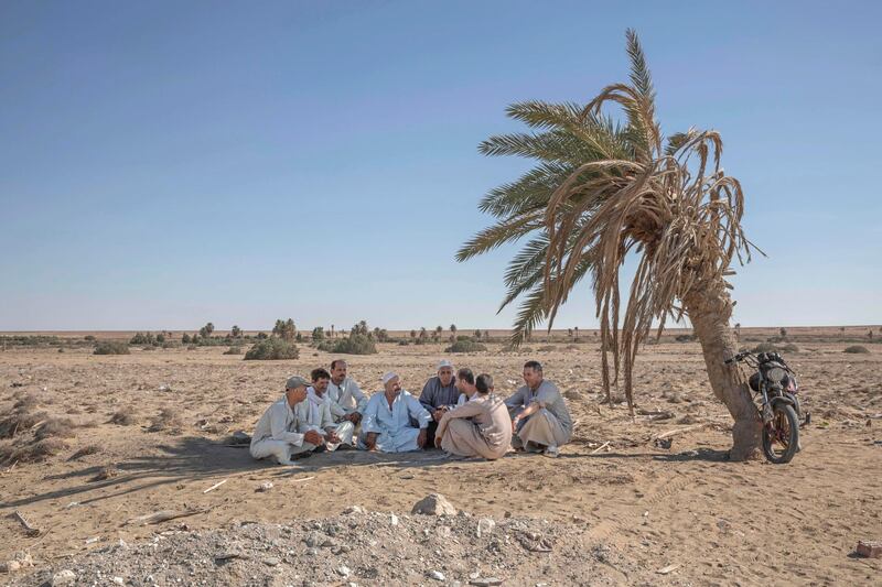 55-year-old Egyptian farmer Makhluf Abu Kassem sits with farmers under shade of a dried up palm tree surrounded by barren wasteland that was once fertile and green. AP