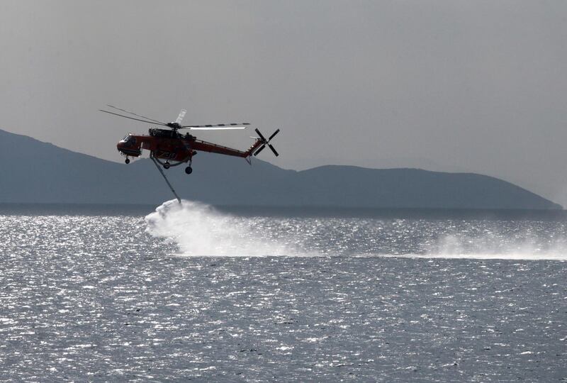 A helicopter collects water near a beach in Mati, close to Nea Makri, in Attica. EPA