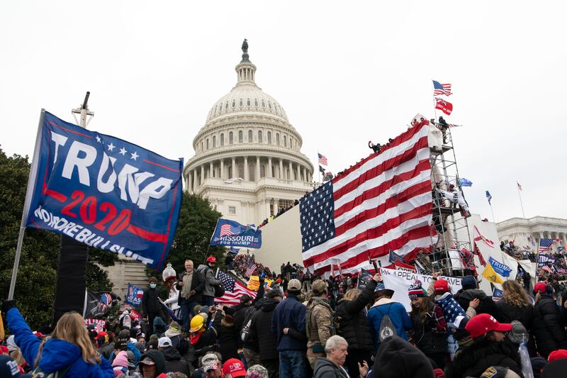 The mob waves pro-Trump flags in front of the Capitol building. AP