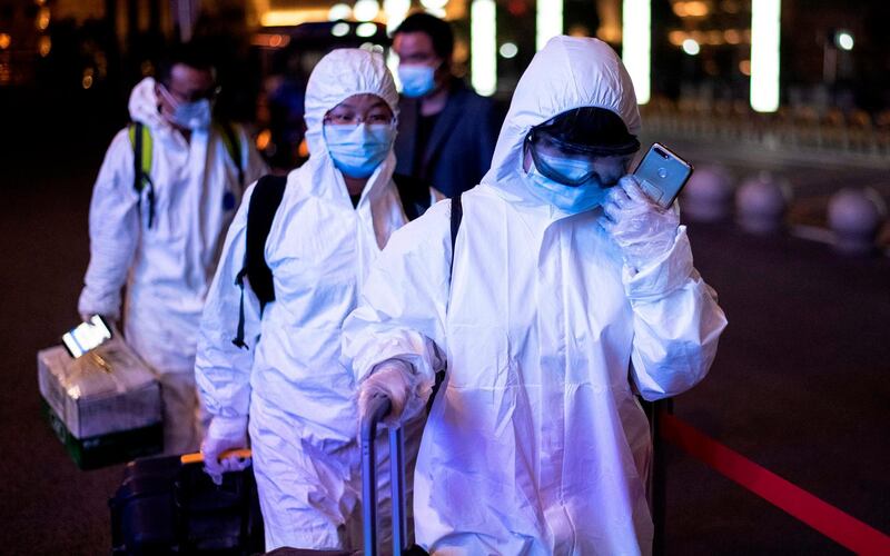 Passengers wear hazmat suit as they arrive at the Wuhan Wuchang Railway Station in Wuhan.  AFP