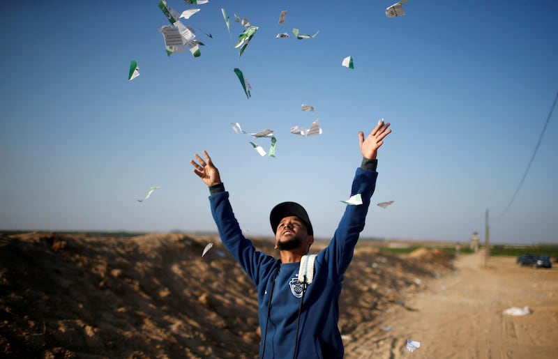 A Palestinian man throws leaflets dropped by the Israeli military during a protest against the US embassy move to Jerusalem and ahead of the 70th anniversary of Nakba, at the Israel-Gaza border, east of Gaza City. Mohammed Salem / Reuters