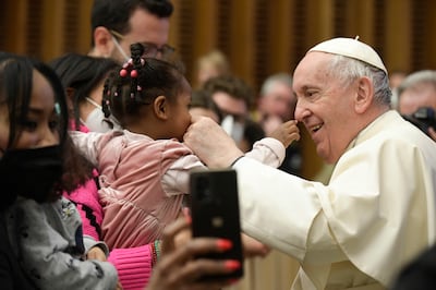 Pope Francis greets a child at the end of the weekly general audience in the Vatican City on March 2, 2022. Vatican Media /  EPA