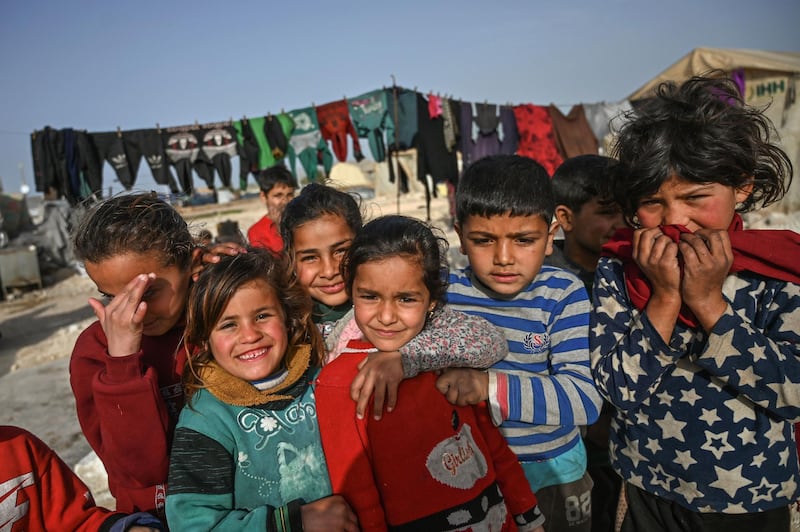 Displaced Syrian children pose for a picture at a camp created by Turkey's Humanitarian Relief Foundation (IHH) in Kafr Lusin village on the border with Turkey in Syria's northwestern province of Idlib. When protesters in March 2011 demanded their rights and regime change, they likely never imagined it would trigger a reaction that has led to the 21st century's biggest war. Nine years on, President Bashar al-Assad is still in power and there to stay, more than 380,000 people have died, dozens of towns and cities razed to the ground and half of the country's entire population displaced.  AFP