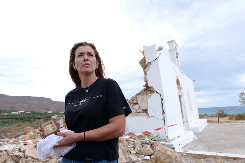 A woman holds a religious icon as she stands in front of a damaged church in Xerokampos village on the island of Crete in Greece, where a 6.3-magnitude earthquake occurred on October 12, 2021. EPA