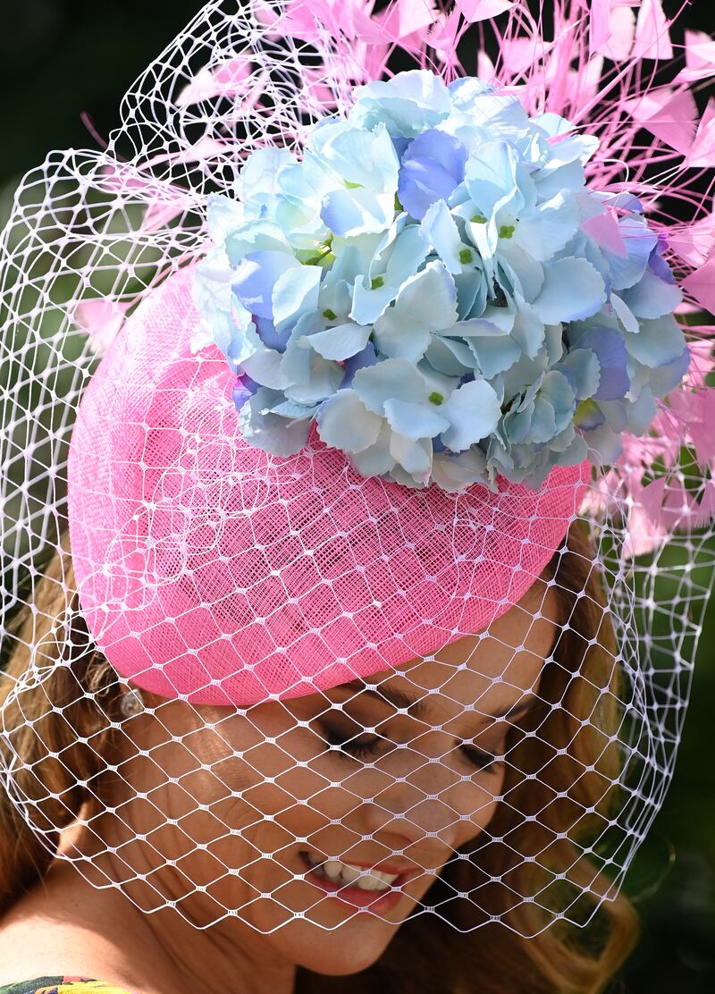 A racegoer wears baby pink and light blue headgear with lacy detail. EPA