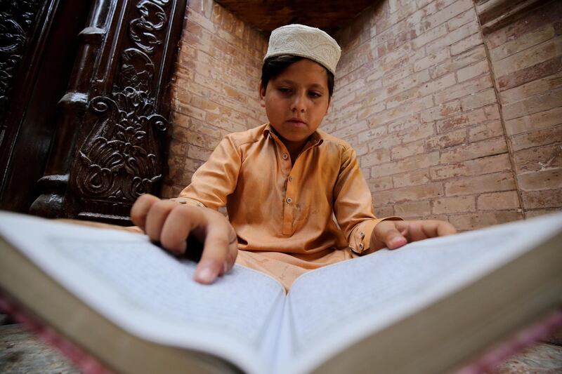 epa09169550 A Pakistani Muslim boy reads verses from the holy Koran at a Mosque during the fasting month of Ramadan, amid the coronavirus pandemic in Peshawar, Pakistan, 30 April 2021. Muslims around the world celebrate the holy month of Ramadan by praying during the night time and abstaining from eating, drinking, and sexual acts during the period between sunrise and sunset. Ramadan is the ninth month in the Islamic calendar and it is believed that the revelation of the first verse in Koran was during its last 10 nights.  EPA/BILAWAL ARBAB