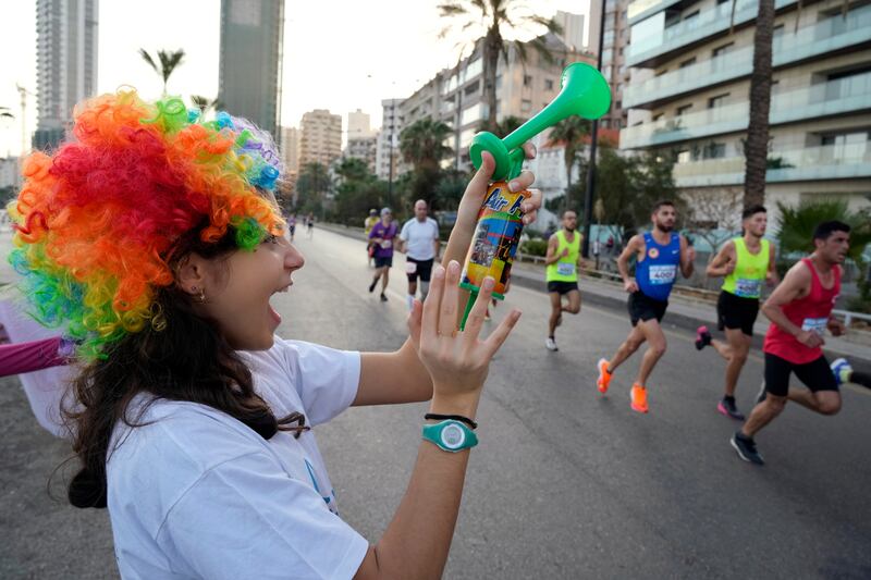 A woman uses an air horn to support the thousands of runners taking part. AP