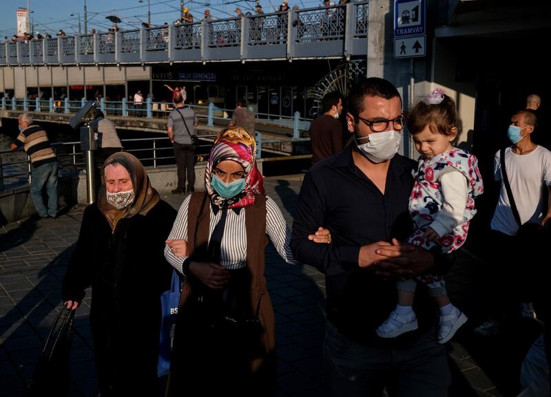 People wear face masks as they walk next to the Galata Bridge near Eminonu local bazaar, in Istanbul, Turkey. Turkish authorities have now allowed the reopening of restaurants, cafes, parks and beaches, as well as lifting the ban on inter-city travel, as the country eases the restrictions it had imposed in a bid to stem the spread of the ongoing pandemic of the COVID-19 disease caused by the SARS-CoV-2 coronavirus.  EPA