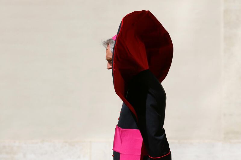 The robe of Archbishop Georg Gaenswein covers his face due to a gust of wind as he waits for French President Emmanuel Macron to arrive for the meeting with Pope Francis at the Vatican, June 26, 2018. Stefano Rellandini / Reuters