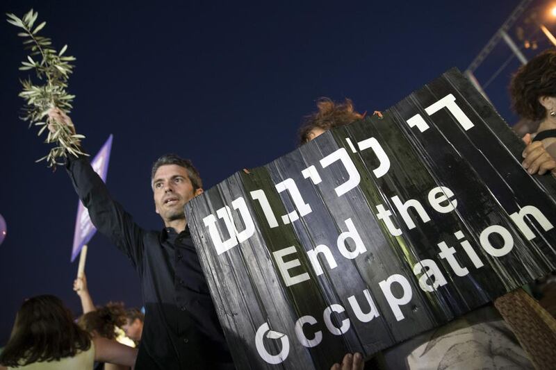 An Israeli left-wing supporter holds a banner during a mass demonstration against 50 years of occupation in Tel Aviv. Photo: Jack Guez / AFP