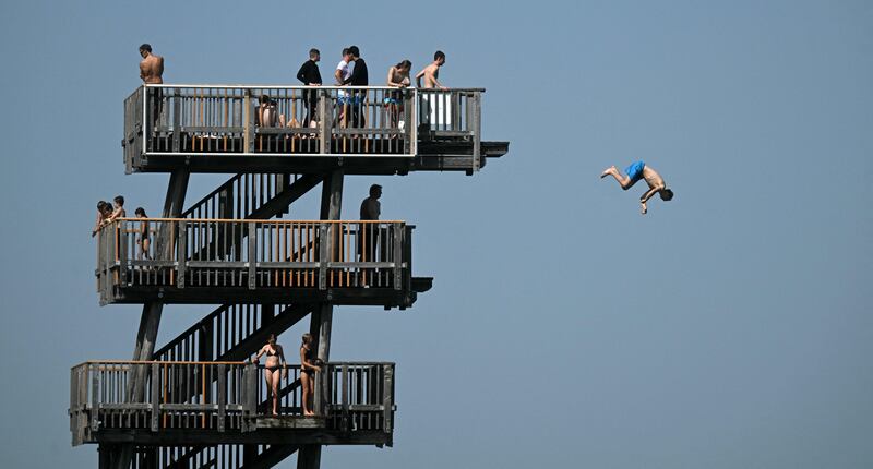 A boy jumping from a diving tower on the shore of lake Ammersee  in southern Germany as the temperature reached around 30°C. AFP