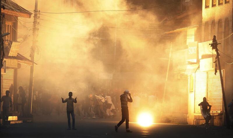 Kashmiri Muslim protesters shout slogans as a tear smoke shell explods near them during clashes between police and protesters in Srinagar.  Farooq Khan / EPA