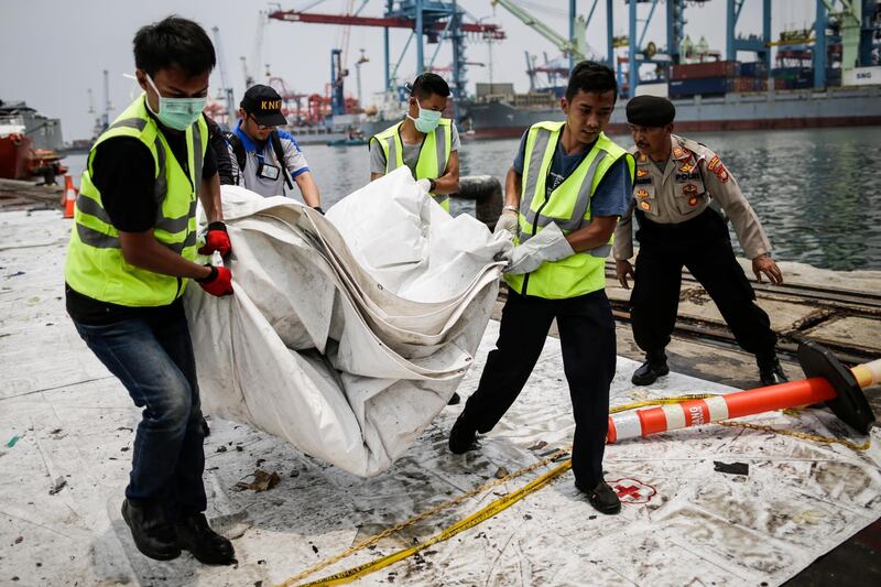 Indonesian rescuers carry recovered debris.