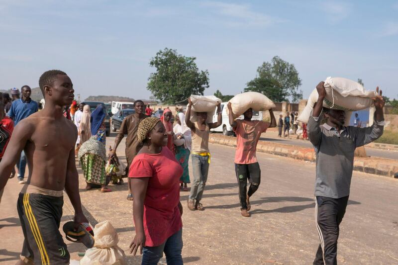 People carry bags of food on their heads during a mass looting of a warehouse storing Covid-19 food supplies in Jos, Nigeria. Nigeria, with 200 million inhabitants, counts the highest number of extreme poverty in the world, with close to 90 million inhabitants who are at food risk. AFP