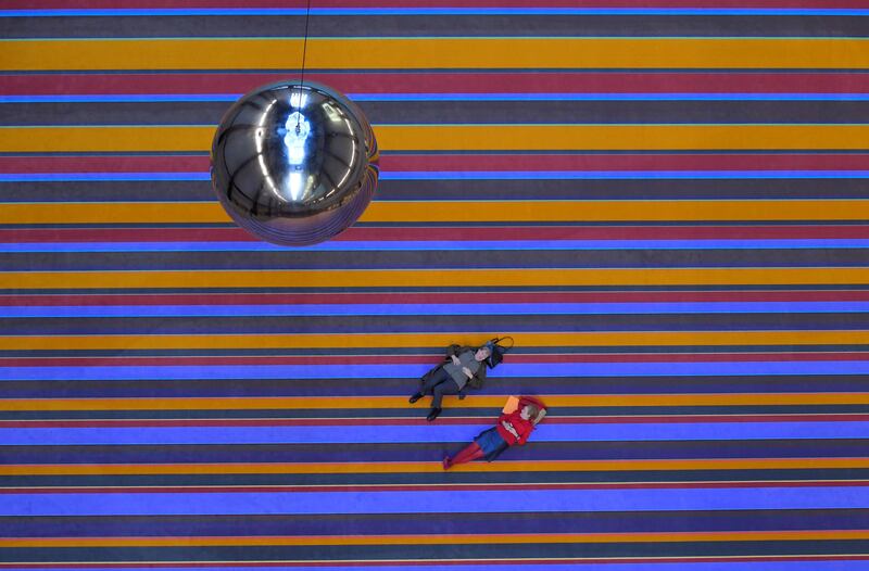 Patrons at the Tate Modern in London lie on a huge carpet to view view a swinging pendulum suspended from the roof - part of the new installation 'One Two Three Swing!' by Danish art collective SUPERFLEX. Toby Melville / Reuters