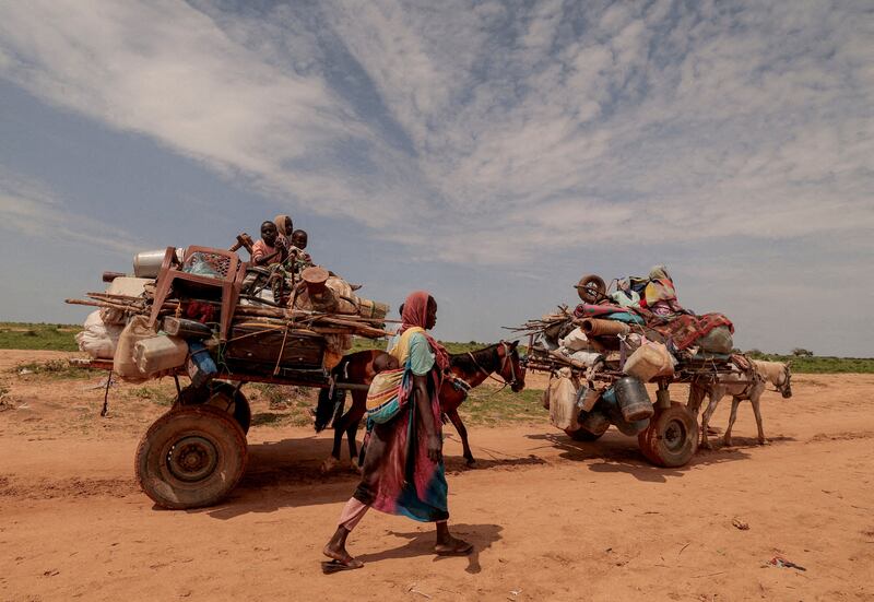 A Sudanese woman, who fled the conflict in Sudan's Darfur region, walks beside carts carrying her family belongings upon crossing the border between Sudan and Chad. Reuters