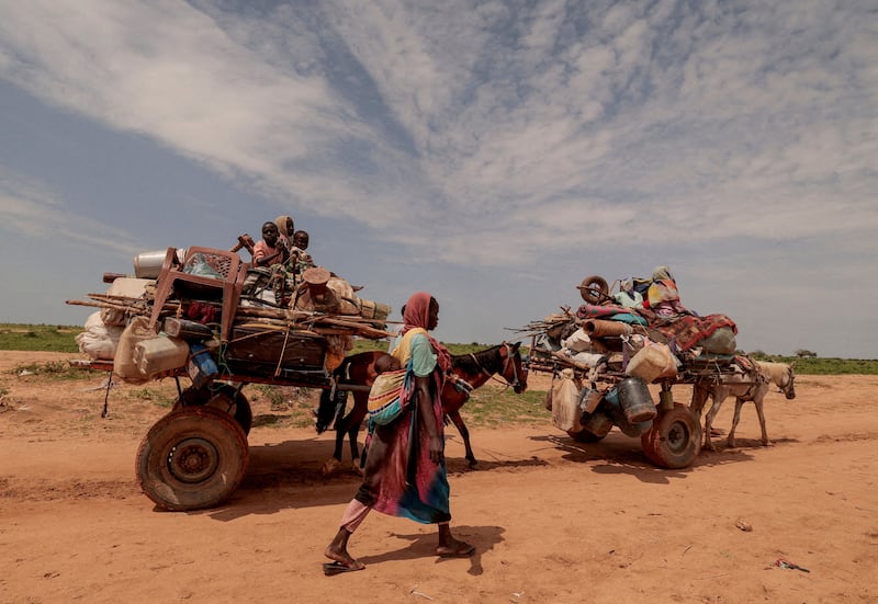 A Sudanese woman, who fled the conflict in Sudan's Darfur region, walks beside carts carrying her family belongings upon crossing the border between Sudan and Chad. Reuters