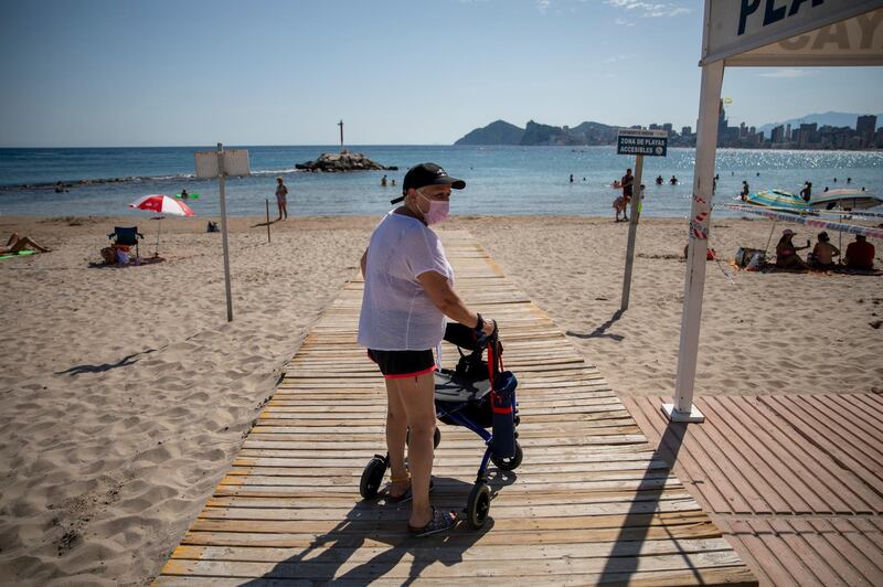 A woman, who is still recovering from long term effects of coronavirus, walks to the beach during a trip organised for vaccinated senior citizens in Benidorm, Spain. Getty Images