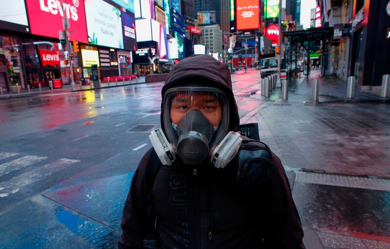 A man wears a face mask while he visits Times Square as rain falls in New York City. AFP