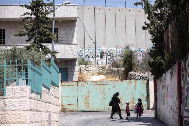 A family along a road in the Aida refugee camp where Israel has built an 8 meter high cement barrier wall .Photo by Heidi Levine for The National