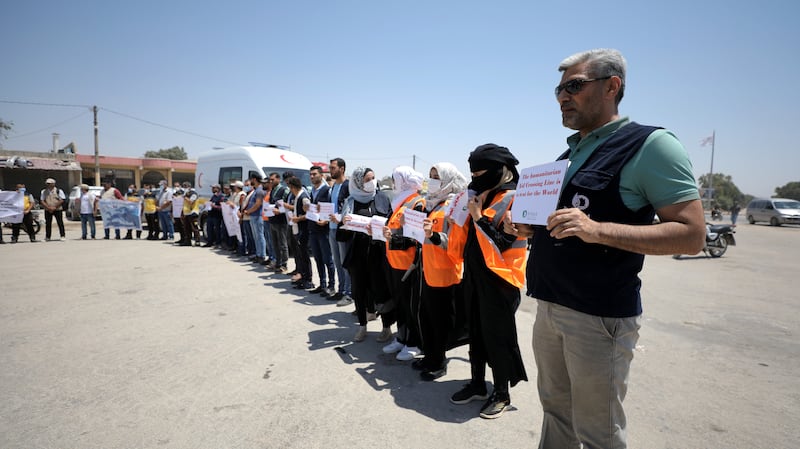 Activists and civil society workers hold placards calling on the international community to maintain the cross-border humanitarian corridor at Bab Al Hawa. EPA