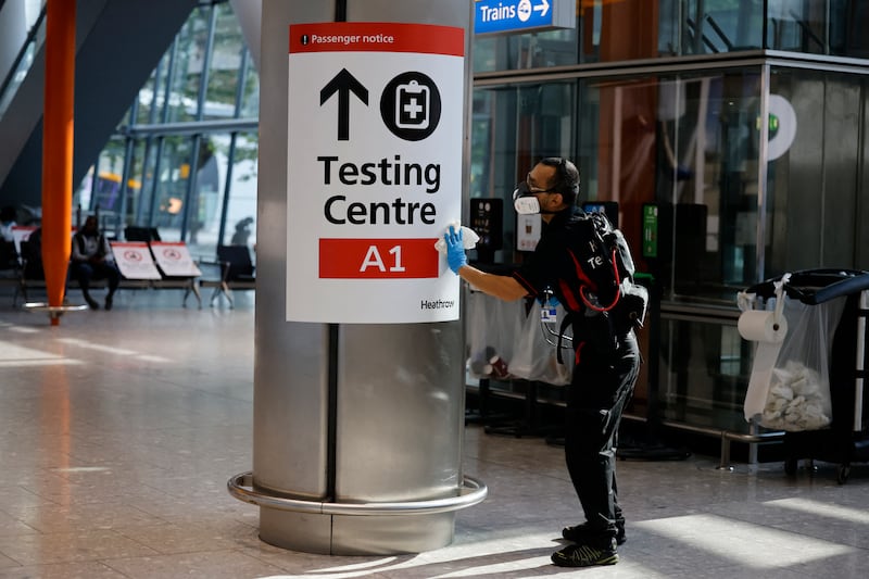 A member of staff cleans a sign at Heathrow's Terminal 5 in west London as quarantine restrictions ease. AFP