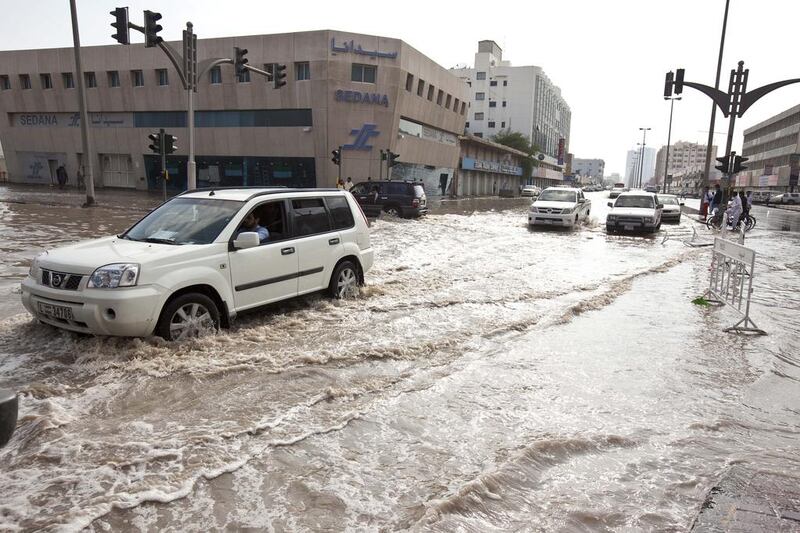 Motorists and pedestrians deal with the heavey flooding in Sharjah's Industrial Area One. Antonie Robertson / The National