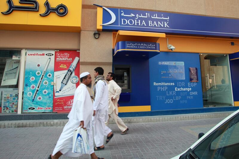 Pedestrians pass a payroll card center operated by Doha Bank QSC in Doha, Qatar, on Thursday, Nov. 22, 2012. Qatar Telecom QSC, the country's biggest company by revenue, is seeking a syndicated loan for about $1 billion to refinance existing debt, according to a person with direct knowledge of the deal. Photographer: Gabriela Maj/Bloomberg
