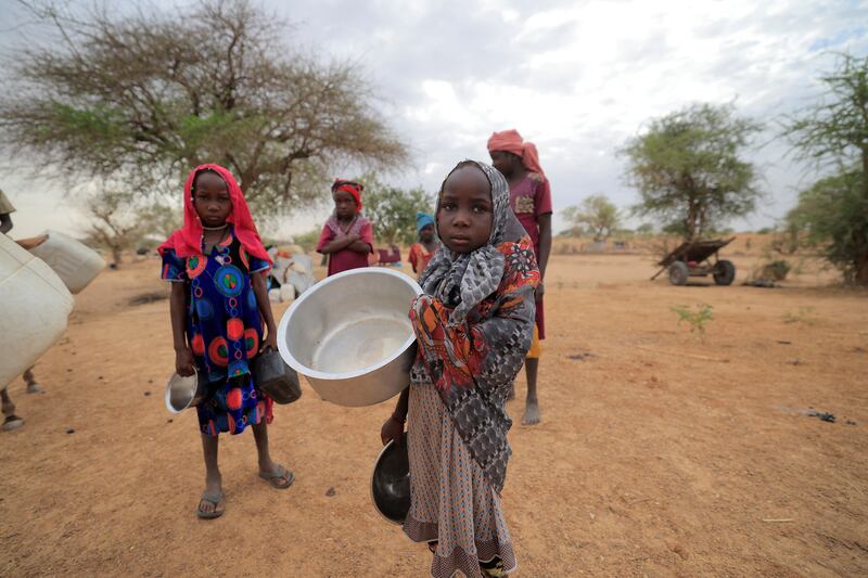 A Sudanese girl who fled the conflict in Sudan's Darfur region carries a pot on her way to collect water near the border between Sudan and Chad on May 12. Reuters