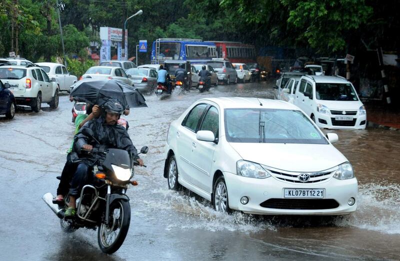 Indian commuters make their way along a waterlogged road during heavy monsoon rains in Kochi. AFP
