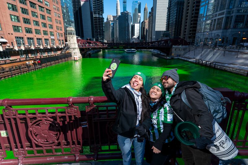 People take a selfie with the green river in the background. AP