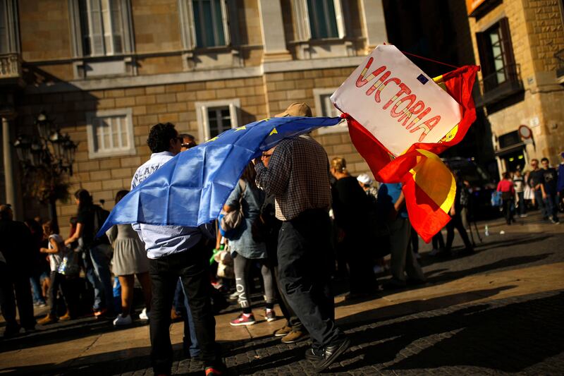 A man holds Spanish and European Union flags and a board reading: "Victory" outside the Palau de la Generalitat in Barcelona, Spain, Monday Oct. 30, 2017. Catalonia's civil servants face their first full work week since Spain's central government overturned an independence declaration by firing the region's elected leaders. (AP Photo/Francisco Seco)