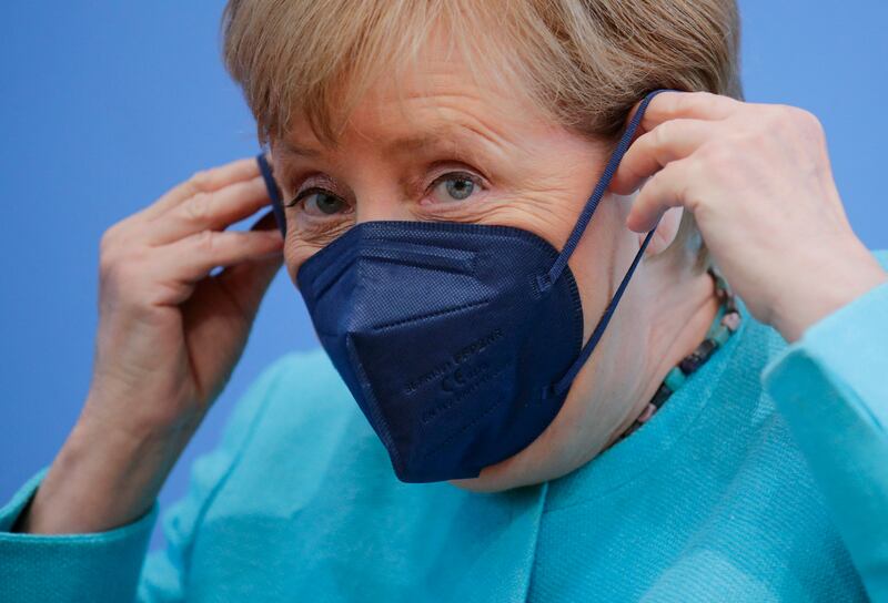 German Chancellor Angela Merkel puts on her face mask after holding her annual summer press conference. AFP