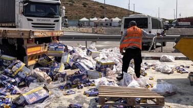 A worker clears packages from damaged aid lorries on the Israeli side of the Tarqumiyah crossing with the occupied West Bank. AFP