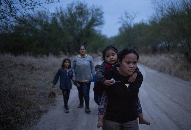 Taznari, an asylum-seeking migrant woman from Honduras, carries her three-year-old daughter, also named Taznari, down a dirt road after they crossed the Rio Grande river into the United States from Mexico on a raft in Penitas, Texas, U.S., March 16, 2021. REUTERS/Adrees Latif