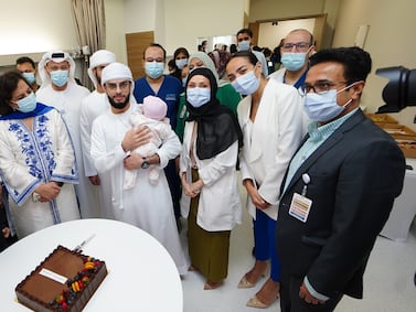 Baby Fatima is pictured with her father Suliman and the medical team following her life-saving surgery. Photo: ADSCC