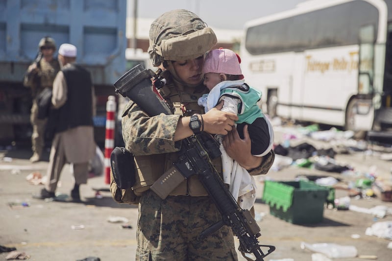 A US Marine carries a baby as the family is processed through the Evacuation Control Centre at the airport in Kabul. AFP