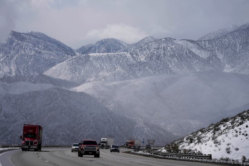 Vehicles make their way along the I-15 as clouds pass through the snow-covered mountains near Hesperia. AP