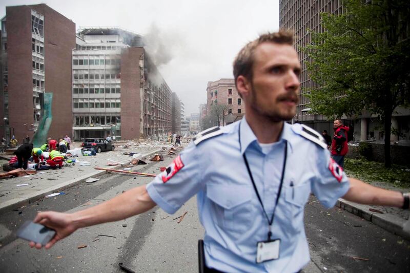 An official attempts to clear away spectators from buildings in the center of Oslo, Friday July 22, 2011, following an explosion that tore open several buildings including the prime minister's office, shattering windows and covering the street with documents. (AP Photo/Fartein Rudjord)  NORWAY OUT *** Local Caption ***  CORRECTION Norway Explosion.JPEG-0415f.jpg