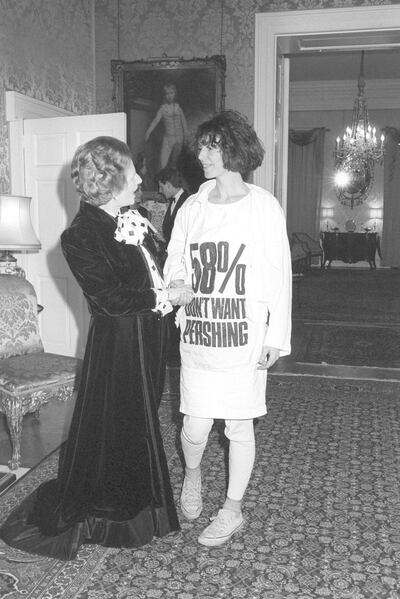 Prime Minister Margaret Thatcher greets fashion designer Katharine Hamnett, wearing a t-shirt with a nuclear missile protest message, at 10 Downing Street, where she hosted a reception for British Fashion Week designers.