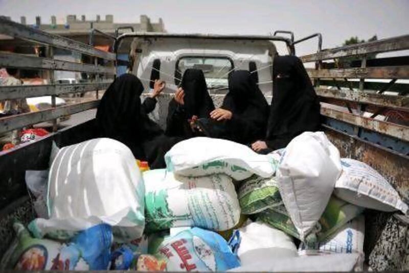 Yemeni women in Sanaa sit next to sacks of food aid provided by the UAE.