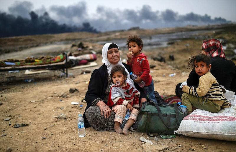 Iraqi families displaced by the operation to retake the city of Mosul from ISIL gather in an area near Qayyarah on October 28, 2016. Bulent Kilic / AFP