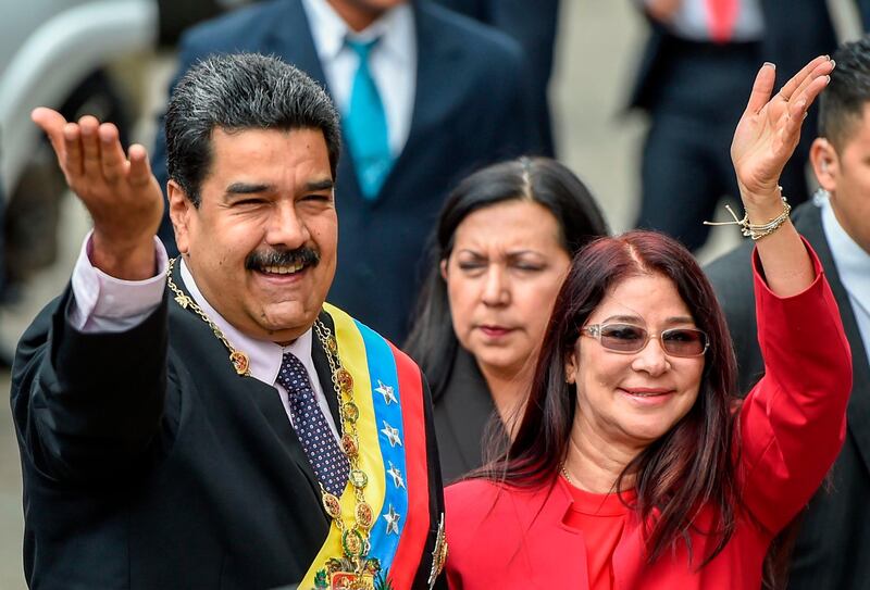 (FILES) In this file photo taken on January 15, 2017 Venezuelan President Nicolas Maduro (L) and his wife, Cilia Flores wave to supporters before the ceremony where Maduro will deliver a speech reviewing his year in office at the Supreme Court of Justice in Caracas. The US Treasury went after Venezuelan President Nicolas Maduro's inner circle on September 25, 2018, imposing sanctions on his wife and other close associates. Treasury named Cilia Adela Flores de Maduro, a former attorney general and the president's wife, as one of the figures who has helped Maduro retain his grip on power. / AFP / JUAN BARRETO
